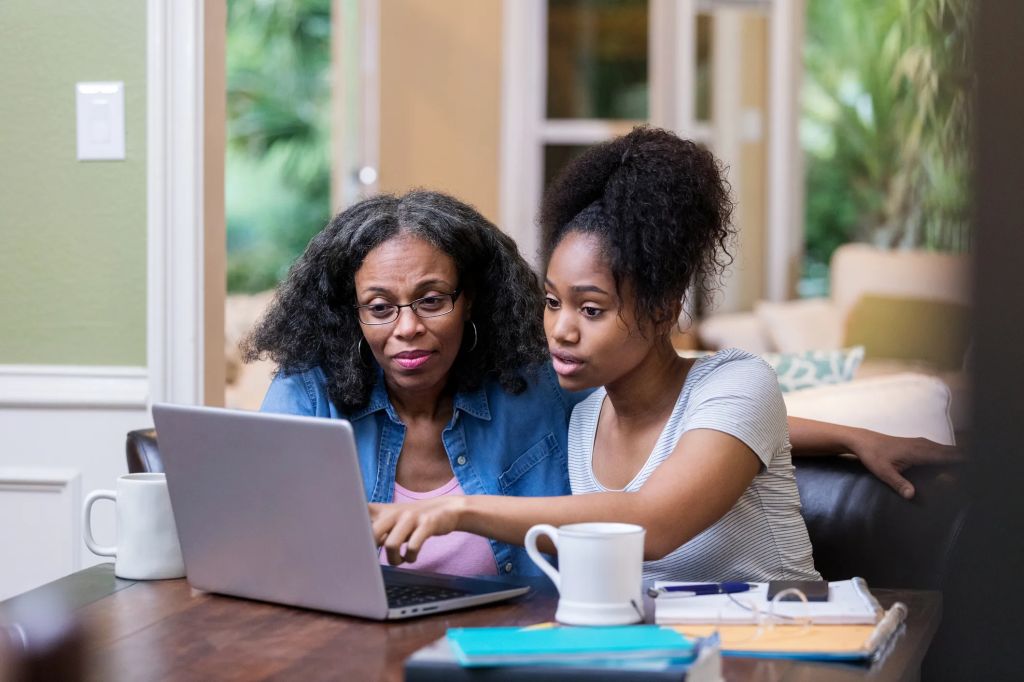An older female parent and her teenage daughter researching online options for Life Insurance for older parents.