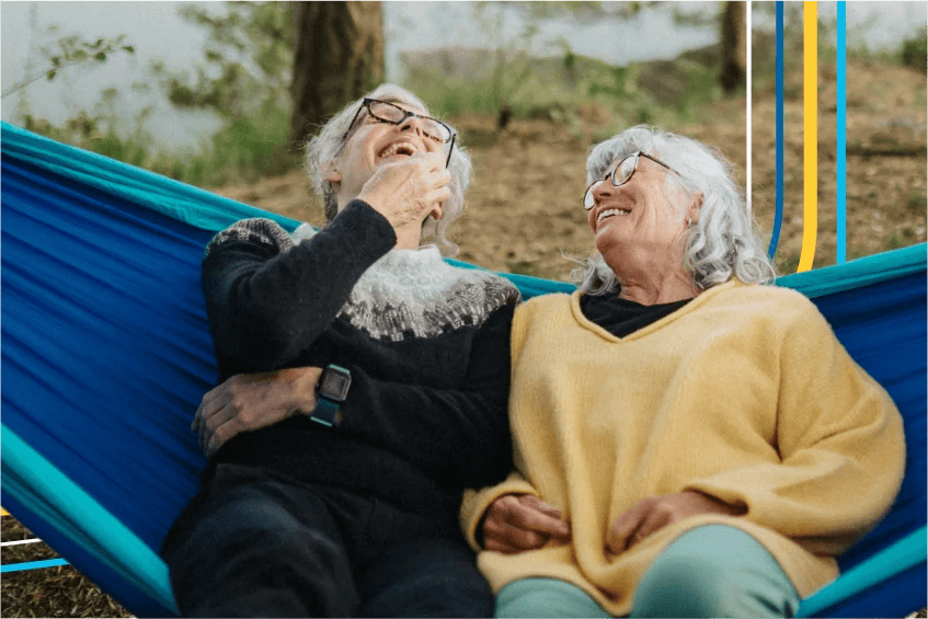 Mature couple laughing together while sitting in a hammock.