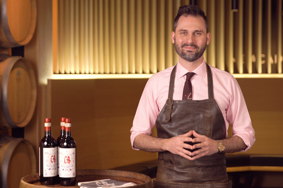 Franco Stalteri posing beside bottles of wine, ready to share knowledge.