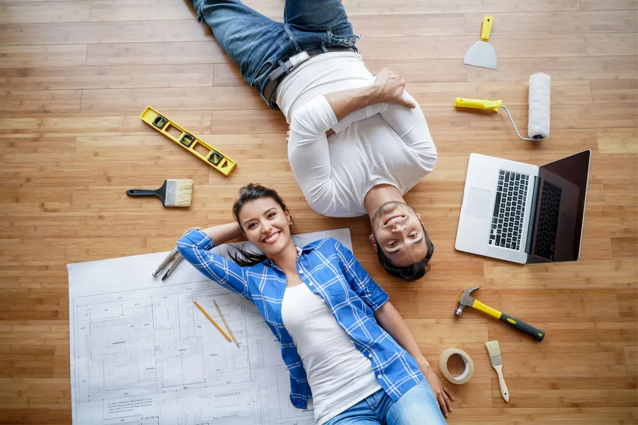 A couple laying down on floor with home maintenance equipment and smiling.