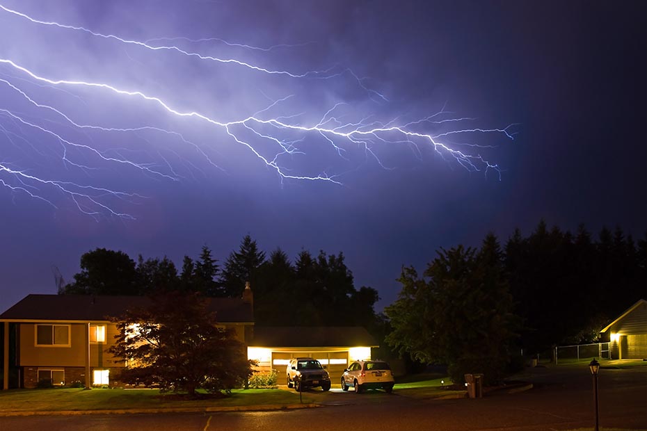 Lighting over a house during a storm at night.