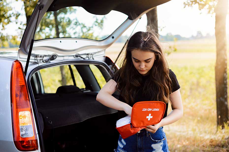 Women pulled over on side of road holding a first aid kit.