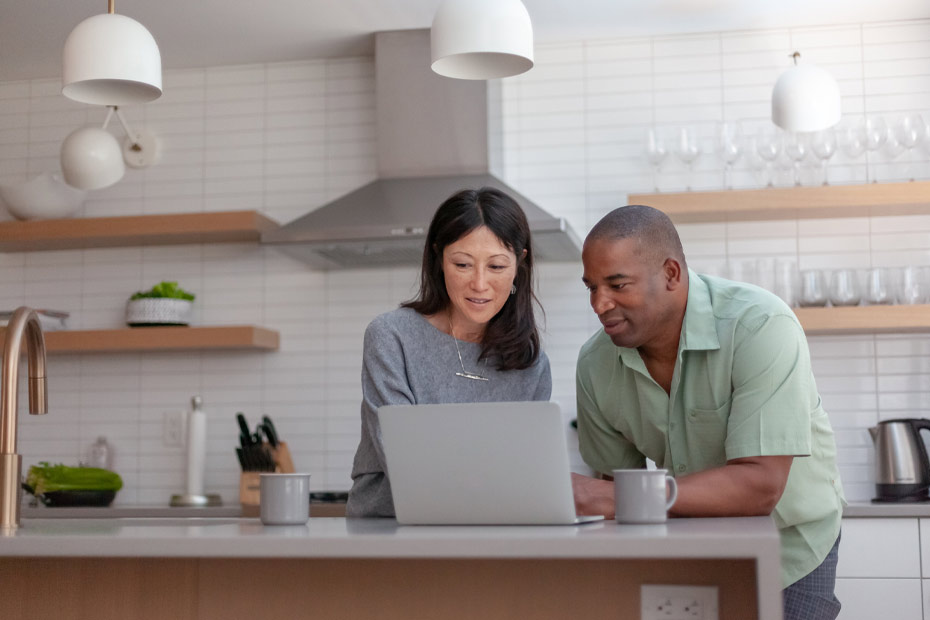 Un couple d'âge moyen dans leurscuisine examine sur un ordinateur portable les options de rentes immédiates réversibles RBC pour le revenu de retraite.