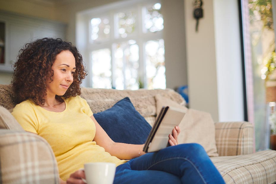 Femme assise sur la tablette de lecture de canapé.
