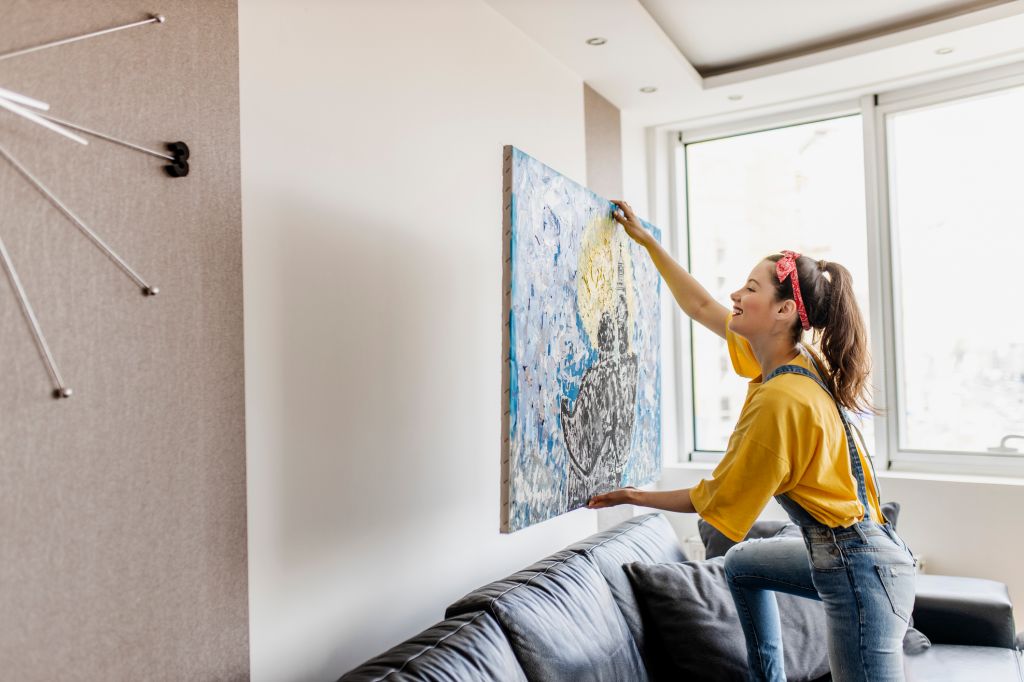 Jeune femme accrochant une image d’art au mur et décorant le salon